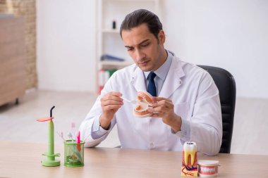 Genç erkek doktor stomatolojist klinikte çalışıyor.