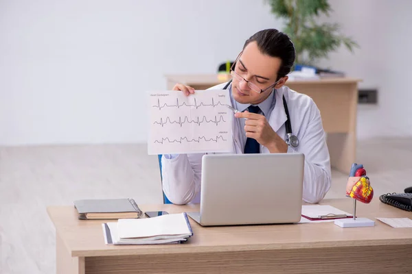 Young male doctor cardiologist looking electrocardiogram — Stock Photo, Image