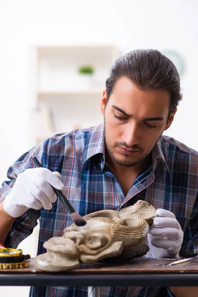 Jonge mannelijke archeoloog bestudeert het oude Afrikaanse steenmasker — Stockfoto