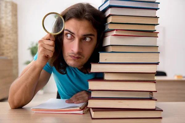 Jonge mannelijke student en veel boeken in de klas — Stockfoto