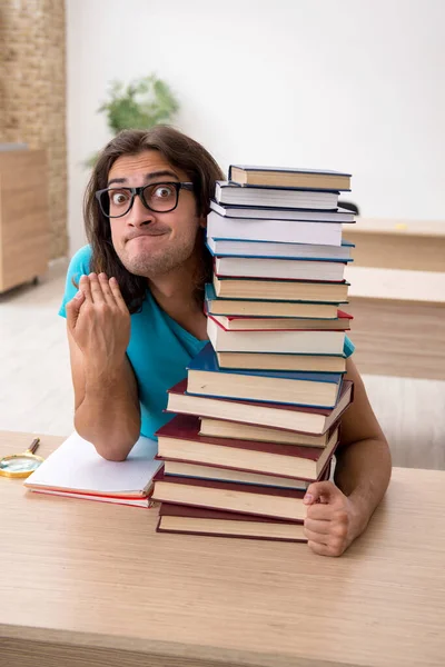 Giovane studente maschio e un sacco di libri in classe — Foto Stock