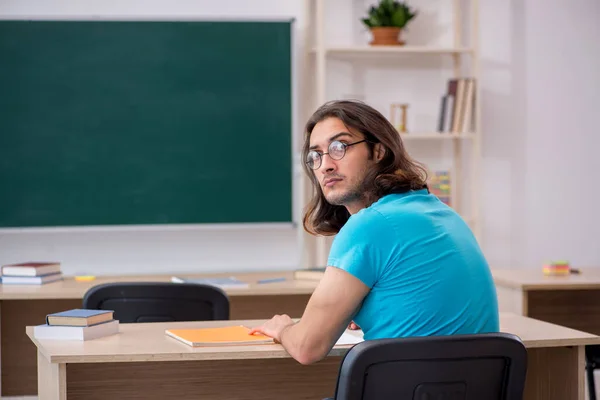 Jonge mannelijke student voor het groene bord — Stockfoto