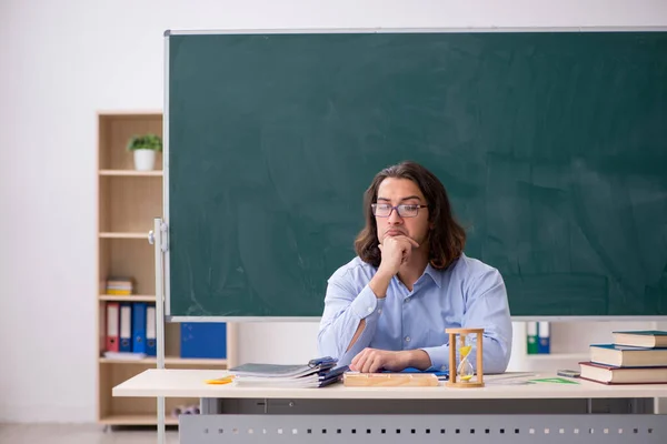 Genç erkek öğretmen yeşil panonun önünde. — Stok fotoğraf