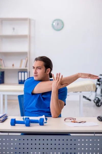 Young male doctor physiotherapist doing sport exercises — Stock Photo, Image