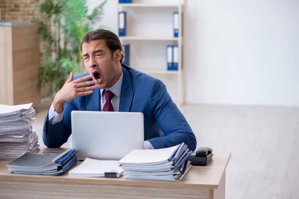 Jonge mannelijke werknemer ongelukkig met overmatig werk in het kantoor — Stockfoto