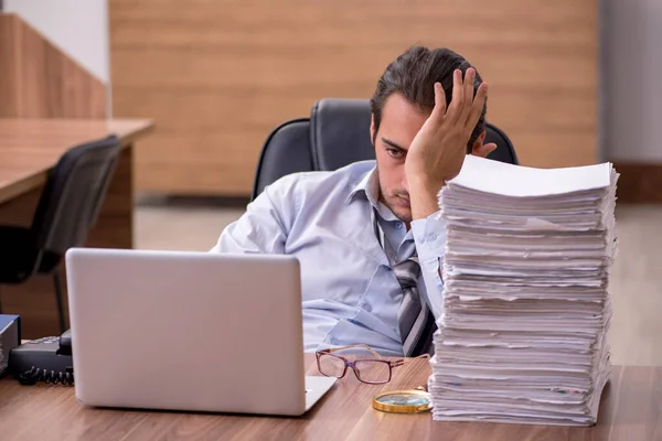 Jonge mannelijke werknemer ongelukkig met overmatig werk in het kantoor — Stockfoto