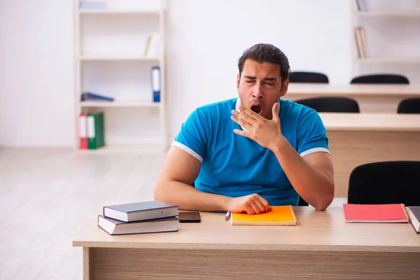 Erschöpfte männliche Schüler bereiten sich im Klassenzimmer auf die Prüfungen vor — Stockfoto