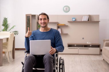 Evde acı çeken tekerlekli sandalyedeki genç adam.