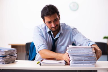 Ofisteki aşırı işten memnun olmayan genç bir erkek işçi.