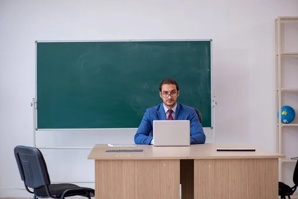 Junger männlicher Lehrer im Anzug vor grünem Brett — Stockfoto