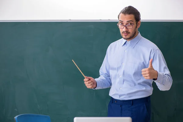 Joven profesor en el aula delante de la mesa verde —  Fotos de Stock