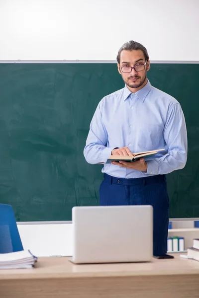 Jeune enseignant masculin dans la salle de classe devant le panneau vert — Photo