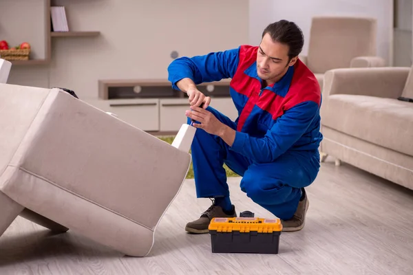 Młody mężczyzna wykonawca naprawiający fotel w pomieszczeniach — Zdjęcie stockowe