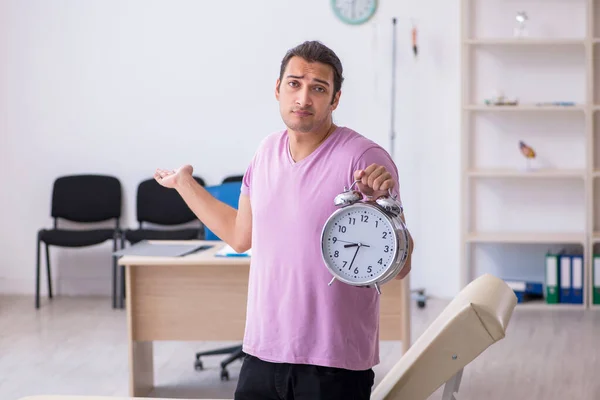 Jonge mannelijke patiënt wachtend op arts in time management concept — Stockfoto