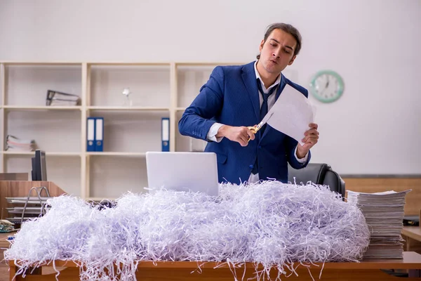 Genç bir erkek çalışan ve ofiste bir sürü kesik kağıt var. — Stok fotoğraf