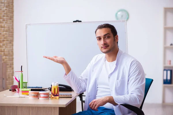 Jonge mannelijke tandarts werkzaam in de kliniek — Stockfoto