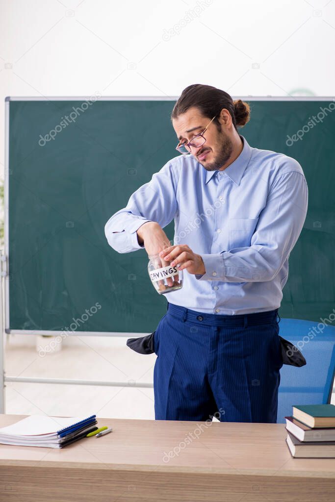 Young underpaid male teacher in the classroom
