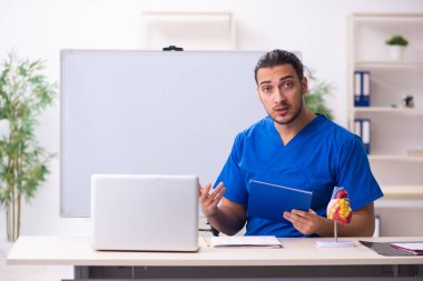 Genç erkek doktor öğretmen kardiyolog beyaz tahtanın önünde.