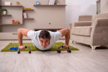Genç adam evde spor yapıyor.