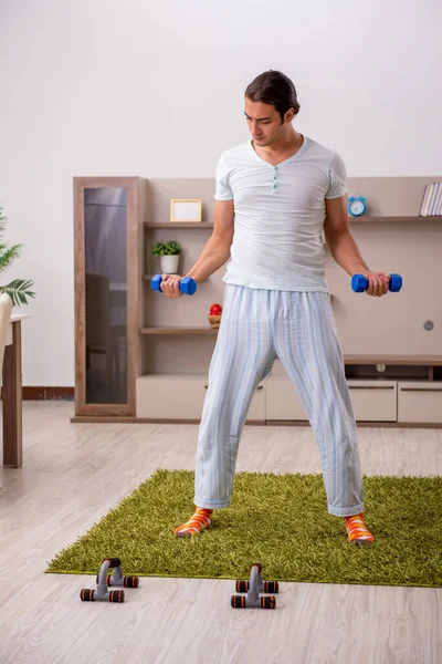 Молодой человек делает спортивные упражнения дома — стоковое фото