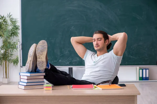 Молодий вчитель чоловічої статі сидить у класі — стокове фото