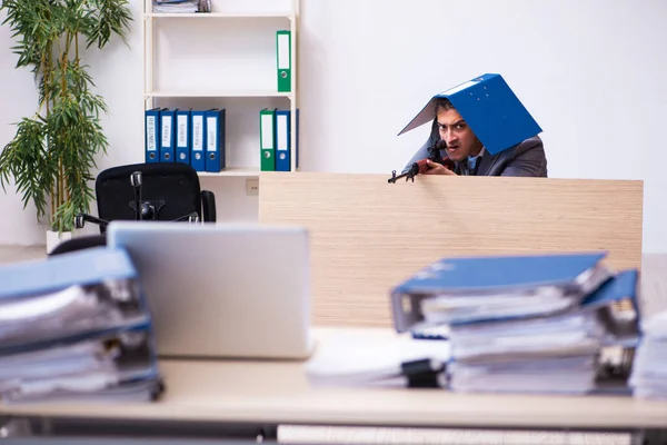 Young employee angry with excessive work holding firearm weapon — Stock Photo, Image