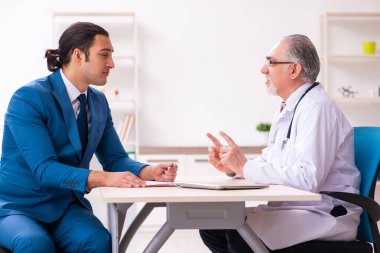 Genç işadamı yaşlı doktorla görüşüyor.