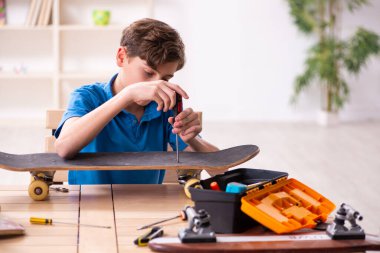 Çocuk evde kaykay tamir ediyor.