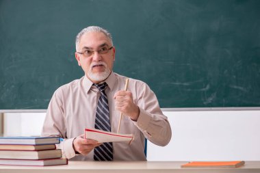 Sınıftaki yaşlı erkek öğretmen.