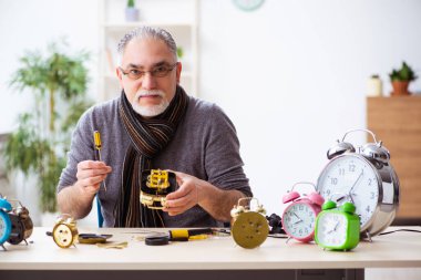Atölyede çalışan yaşlı bir erkek saatçi.