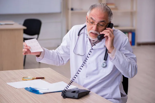 Oude mannelijke cardioloog werkzaam in de kliniek — Stockfoto