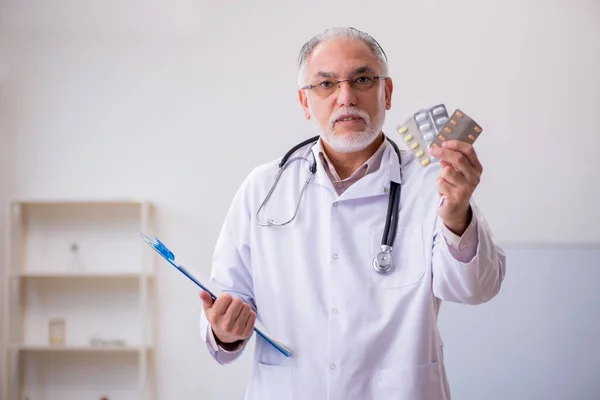 Viejo doctor sugiriendo pastillas en la clínica — Foto de Stock