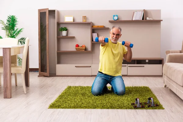 Wiek mężczyzna robi ćwiczenia sportowe w domu — Zdjęcie stockowe