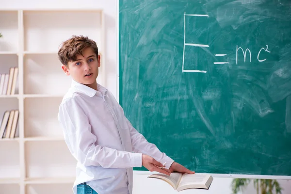 Schooljongen natuurkundige voor het groene bord — Stockfoto