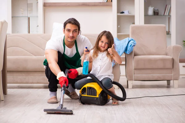 Jovem empreiteiro limpando a casa com sua filha pequena — Fotografia de Stock