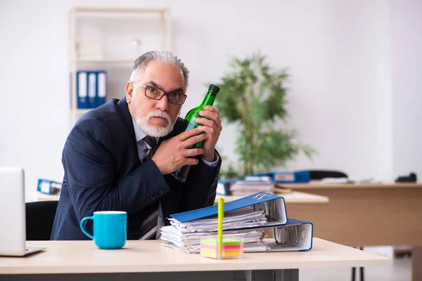 Старый работник-мужчина пьет алкоголь в офисе — стоковое фото