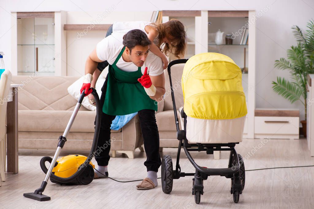 Young male contractor cleaning the house with his small daughter