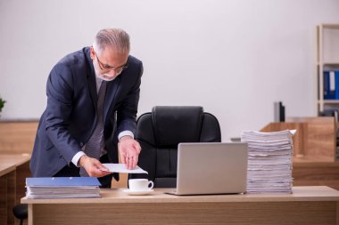 Ofiste gazete okuyan yaşlı bir erkek.