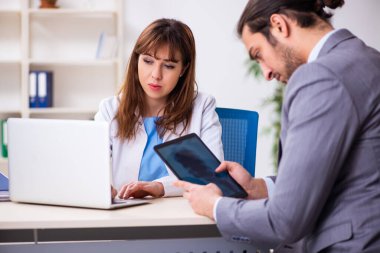 Genç bayan doktor ve hasta iş adamı ofiste.