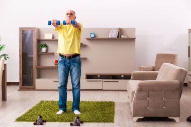 Yaşlı adam evde spor egzersizleri yapıyor.