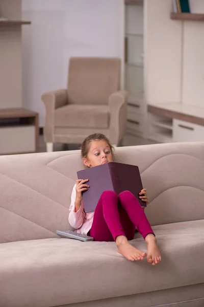 Liten flicka läser bok hemma — Stockfoto