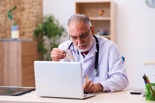 Viejo médico masculino sosteniendo píldoras —  Fotos de Stock