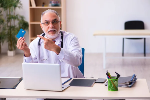 Old male doctor holding credit card — Stock Photo, Image