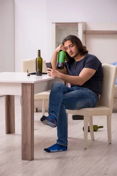 Fiatal munkanélküli férfi, aki otthon iszik alkoholt — Stock Fotó