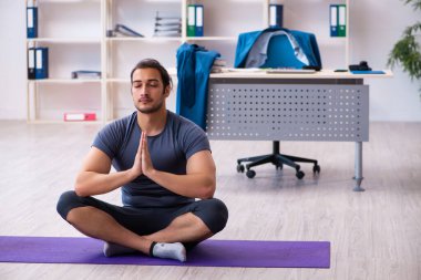 Genç yakışıklı çalışan ofiste spor egzersizleri yapıyor.