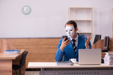 Ofiste maske takan genç bir erkek.