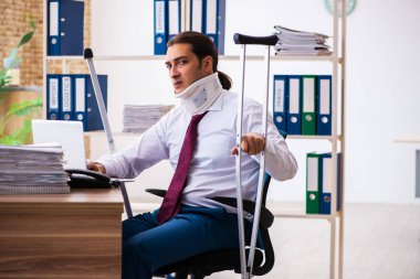 İş yerinde koltuk değnekleriyle yaralı erkek çalışan.