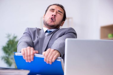 Ofisteki aşırı işten memnun olmayan genç bir erkek işçi.