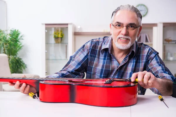 Hombre mayor reparador reparando instrumentos musicales en casa —  Fotos de Stock