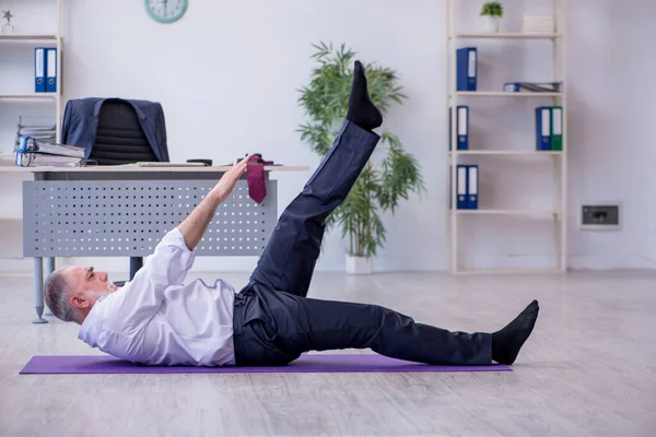 休憩中に体操をする高齢男性従業員 — ストック写真